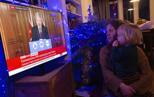 英총리영국 런던에 거주 중인 가족이 보리스 존슨 영국 총리의 기자회견을 시청하고 있다. 코로나19 변종이 빠른 속도로 확산하자 존슨 총리는 19일(현지시간) 4단계를 신설하고 런던과 잉글랜드 남동부 등에 이를 적용했다.     런던=EPA 연합뉴스